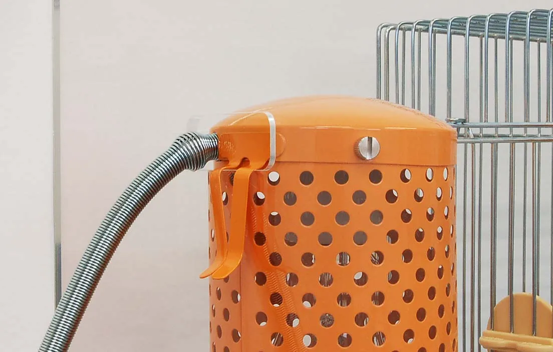 鳥かごを覆うアクリルケースとヒーター設置例の画像。ケージ外側の隙間にヒーターを配置するWIDEタイプの設置方法を示す。